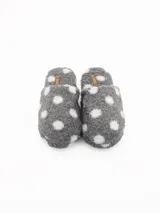 Pantuflas de estar por casa confeccionadas en tejido de peluche suave, con diseño de lunares blancos sobre fondo gris. Cuentan con una etiqueta pequeña de marca en la parte superior.