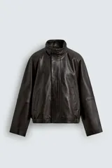 Cazadora bomber de corte relajado confeccionada en piel. Presenta cuello subido, manga larga ranglán, bolsillos de vivo en la cadera y bajo con elástico. Cierre frontal con cremallera oculta por solapa con botones a presión.