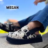 Zuecos cerrados de cuero con plataforma negra y diseño estampado estilo cow print en blanco y negro. Posee una tira lateral con hebilla metálica de estilo western.