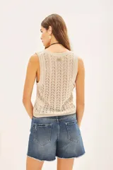 Musculosa sin mangas de tejido punto desagujado en color beige claro, con patrón de rombos calados y brillo sutil por el hilado de lurex y lentejuelas.