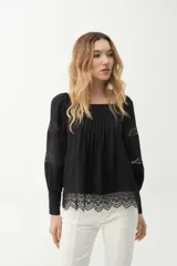 Blusa negra con escote cuadrado, mangas largas abullonadas con detalles de encaje y galón de encaje en el ruedo.