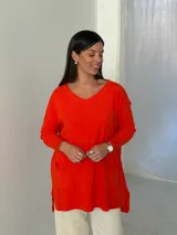 Sweater de punto color naranja, con cuello en V, manga larga y diseño holgado con bolsillos frontales y tajos laterales.