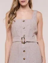 Vestido midi abotonado verde melange, con escote recto, tirantes anchos y falda de calce recto con vuelo sutil. Tiene abotonadura frontal completa con botones estilo carey, cinto textil con hebilla para ajustar la cintura y bolsillos laterales.