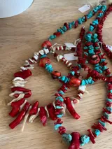Collar hecho a mano con cuentas de coral rojo y nácar blanco, engarzadas en cadena metálica plateada.