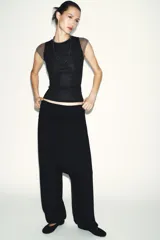 Top de manga caída, con efecto de doble capa. La capa exterior es negra y ajustada, mientras que la capa interior, visible en mangas y cuello, es de color marrón topo.