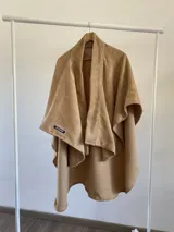 Ruana de tela tipo tapiz con textura waffle, color dorado, de corte abierto y diseño envolvente.