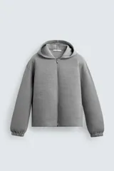 Sudadera gris de corte boxy fit con capucha y cierre frontal de cremallera. Confeccionada en tejido doble y compacto, cuenta con bolsillos laterales ocultos en la cadera y mangas largas con puños elásticos.