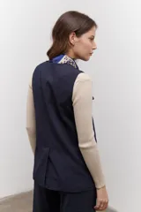 Chaleco azul con cuello en V y cierre frontal con botones marrones.