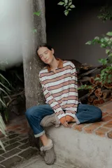 Remera de manga larga con cuello polo y cierre frontal de botones. Presenta un diseño a rayas horizontales en tonos bordó, blanco y celeste.