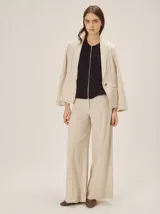 Pantalón sastrero de corte ancho, color beige con rayas verticales blancas y detalles de costuras pespunteadas.