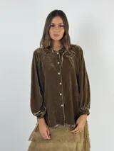 Camisa color marrón de terciopelo de viscosa, con cuello camisero, cierre frontal con botones, mangas largas abullonadas con puños elásticos y corte holgado.