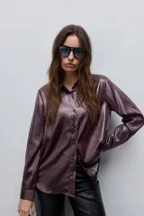 Camisa blanca de calce relajado con acabado satinado y brillo sutil, cuello clásico, cierre frontal con botones y mangas largas con puños.