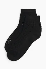 Medias tobilleras de color negro, confeccionadas con un tejido de punto calado estilo crochet y borde elástico superior.