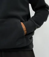 Buzo deportivo de hombre confeccionado en tejido polar (fleece) de color gris oscuro. Presenta capucha con cordones ajustables, bolsillo tipo canguro frontal, mangas largas con puños ajustados y bajo elástico. Su diseño es cerrado y cuenta con una textura suave y cálida ideal para el invierno.