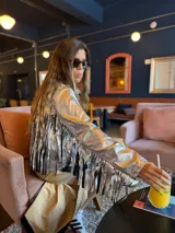 Campera plateada de cuero sintético con flecos en la espalda y mangas.