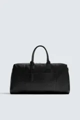 Bolso de viaje negro de cuero con acabado abatanado. Tiene un compartimento principal con cierre de cremallera, un bolsillo interior con cremallera y un bolsillo plano en la parte frontal. Cuenta con dos asas de mano y una correa de hombro ajustable y extraíble. Incluye un detalle de candado.