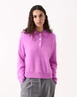 Sweater de punto color fucsia, con cuello polo y tapeta de tres botones blancos. Tejido de pelo suave, manga larga y puños y ruedo ajustados.