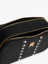 Cartera tipo bandolera de Tommy Hilfiger con acabado granulado, dos compartimentos principales con cierre de cremallera, correa ajustable y detalle de cinta distintiva con monograma TH metálico en la parte frontal.