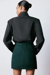 Falda mini de tiro bajo confeccionada en sarga de algodón, con diseño de cinco bolsillos, trabillas en la cintura y cierre frontal con cremallera y ganchos metálicos.
