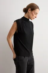 Blusa de lurex negra sin mangas, con cuello alto drapeado y detalle de pliegues frontales.