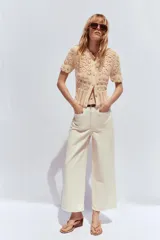 Pantalón de jean color crudo, de tiro alto, corte wide leg cropped y cinturón marrón.