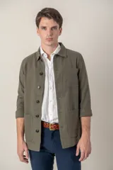 Sobre camisa color verde militar de lino con cuello clásico, manga larga con puños abotonados, cierre frontal con botones a tono y bolsillos de parche en el pecho.