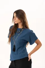 Blusa de silueta relajada y cuello redondo, confeccionada en tela liviana con textura. Presenta mangas cortas y una caída suelta.