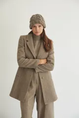 Saco corto entallado de lana fina, con cuello solapa, manga larga y cierre frontal con botones. Presenta un diseño clásico con textura de espiga en tonos tierra.