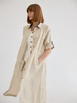 Vestido camisero midi de lino color beige, con diseño de manga corta con solapa, cuello camisero, bolsillo trasero con solapa y botón, y aberturas laterales en el ruedo.