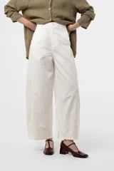 Pantalon blanco de pierna amplia y corte relajado, con cintura alta y detalles de recortes en la parte inferior.