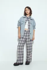 Pantalón de tiro alto, pierna amplia y caída fluida, con estampado de cuadros en tonos blanco, negro y marrón oscuro.