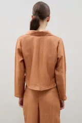 Camisa de manga larga color marrón con textura arrugada, cuello clásico y cierre frontal mediante lazos para anudar.