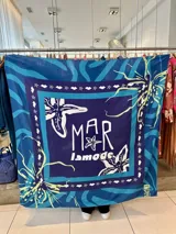 Pañuelo cuadrado de gran tamaño con estampado con motivos marinos en tonos azules, blanco y amarillo. Incluye el logo de la marca.