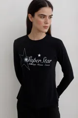 Remera de manga larga con efecto lavado, cuello redondo y estampa frontal con diseño de estrella y texto.
