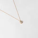 Conjunto compuesto por cadena fina y dije circular con circonia central engastada en oro 18k.