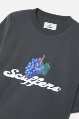 Remera de corte oversized color gris oscuro con efecto lavado, con un gráfico frontal que incluye un racimo de uvas moradas y el texto "Scuffers" en tipografía cursiva blanca.