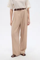 Pantalón de lyocell color beige, de tiro alto, corte ancho y diseño plisado con bolsillos laterales.