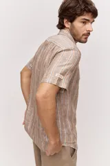 Camisa de manga corta con diseño a rayas verticales en tonos tostado, blanco y azul. Cuenta con cuello clásico y cierre frontal de botones.