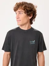 Remera oversize color beige de manga corta, con gran estampa colorida en la espalda con diseño de mapa de playa y la inscripción "Rusty County".