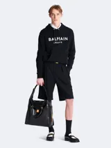 Buzo hoodie negro de algodón con logo Balmain Paris estampado en blanco en el frente.