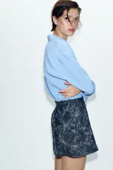 Falda pantalón corta de denim azul oscuro con bordados de flores en hilo metalizado plateado y detalles de lentejuelas.