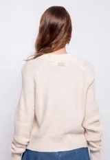 Cardigan de tejido de punto color beige, con diseño de ochos y puntos texturizados, cierre frontal de botones a tono y mangas largas con puños acanalados.