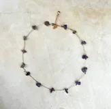 Collar delicado de cadena dorada con pequeñas piedras naturales en tonos variados, dispuestas de forma sutil a lo largo de la pieza.