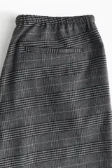 Pantalón holgado de pierna recta y tiro medio, confeccionado en tejido a cuadros gris. Presenta cintura elástica con cordón ajustable y bolsillos laterales.