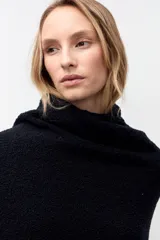 Chal de tejido de punto texturizado en color negro, con diseño envolvente y etiqueta de cuero sintético con logo en el extremo inferior.