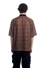 Remera deportiva marrón con cuello polo negro, cierre parcial con cremallera, mangas cortas y estampado con letras.