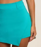 Short pollera corto de bengalina color turquesa, con trabillas en la cintura, diseño cruzado y bajo asimétrico.