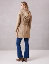Gabardina trench de tejido repelente al agua en color beige. Presenta cuello con solapa ancha, cierre frontal con botones en tono carey, capucha desmontable y lazo de ajuste en la cintura. Incluye bolsillos laterales tipo ojal y forro interno a tono.