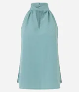 Blusa sin mangas color verde menta, confeccionada en tejido jacquard con textura de pequeños cuadros. Presenta un cuello halter que se anuda o cruza en la parte delantera, creando un escote en V con un recorte central.