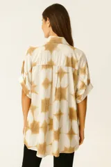 Camisa de corte holgado con estampado de círculos grandes en tonos azul y blanco. Presenta cuello camisero clásico, cierre frontal con botones y mangas cortas con dobladillo.